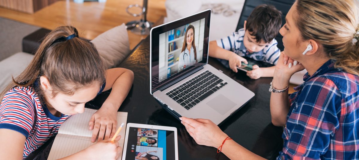 Mother trying to talk with doctor on laptop while watching two kids staying home. Homeschooling and distance learning